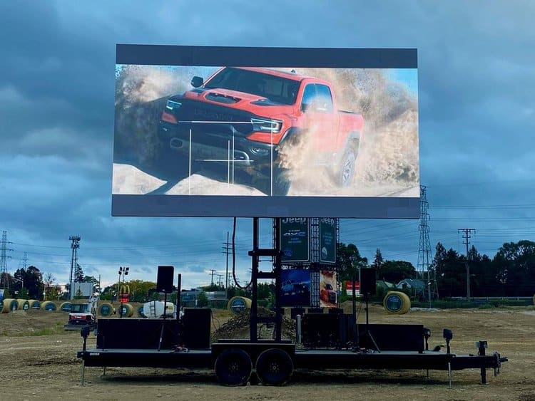 Large mobile LED screen trailer at an outdoor car show
